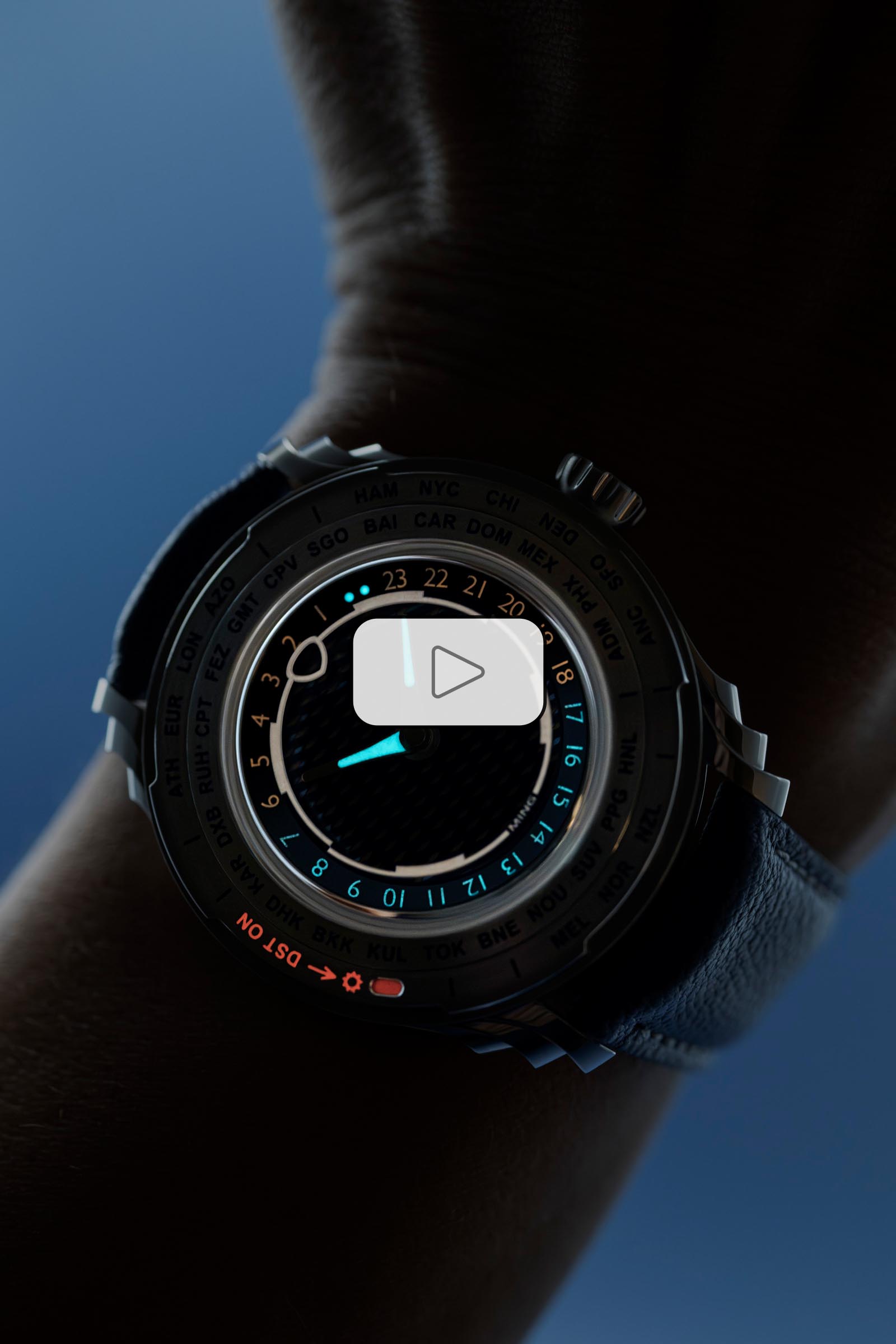 6a8d087268fd3218b626b739 DST ON Ceas MING 57.05 Comet pe încheietura mâinii, afișând ora cu indicatoare luminoase și bezel cu nume de orașe pentru funcția de fus orar.
