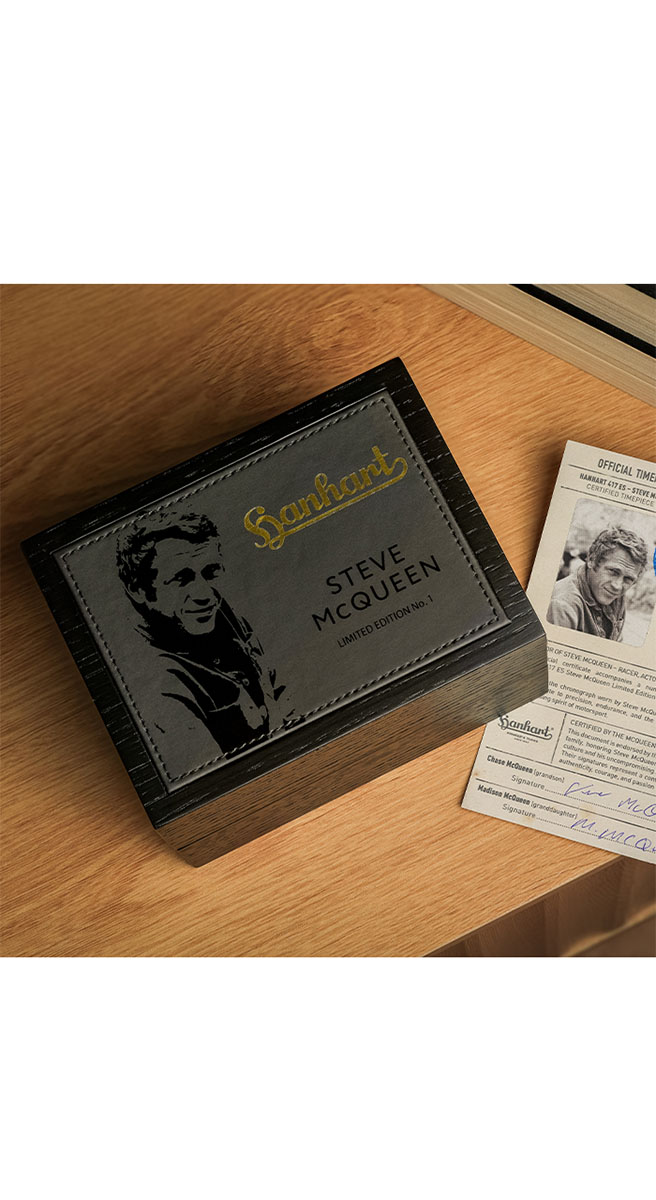 Steve McQueen LE Cutie neagră din lemn cu etichetă gri ce arată portretul lui Steve McQueen și inscripția Hanhart Steve McQueen Limited Edition No.1, pe un birou de lemn lângă un certificat autentic.
